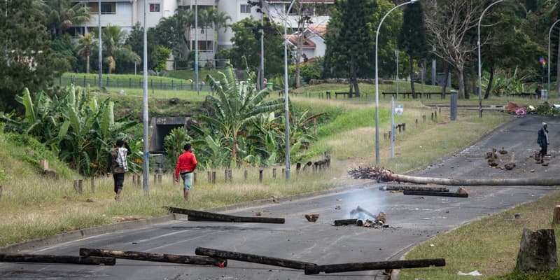 Des habitants marchent le long d'une rue bloquée dans le quartier des Jacarandas à Dumbéa, en Nouvelle-Calédonie, territoire français du Pacifique, le 2 juin 2024. 