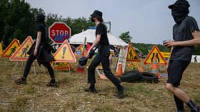 Manifestants devant plusieurs panneaux routiers de travaux, lors de la mobilisation contre l'autoroute A69, près de Puylaurens (Tarn), le 8 juin 2024