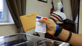 Un électeur tient une carte électorale et un bulletin de vote avant de voter dans un bureau de vote à Etaples, pour le second tour des élections régionales, le 27 juin 2021 (illustration)